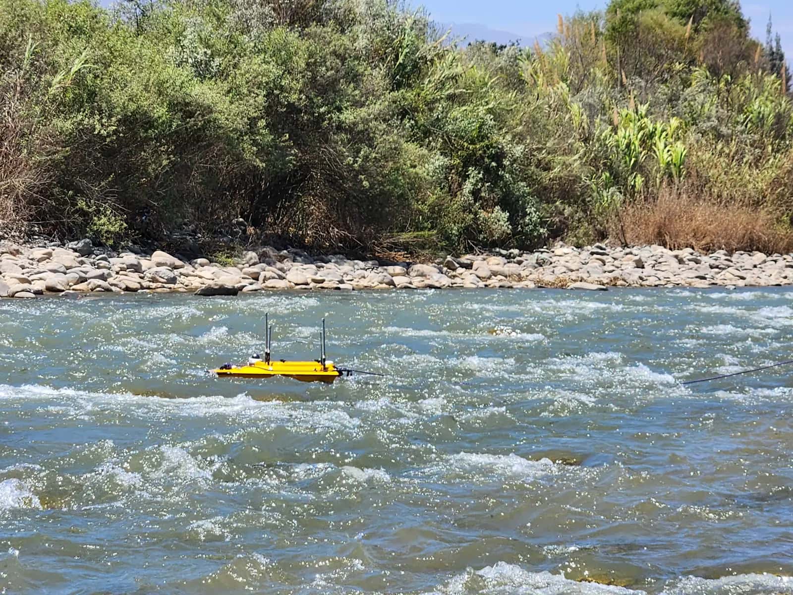 Embarcación no tripulada de batimetría navegando en un tramo de río con corriente