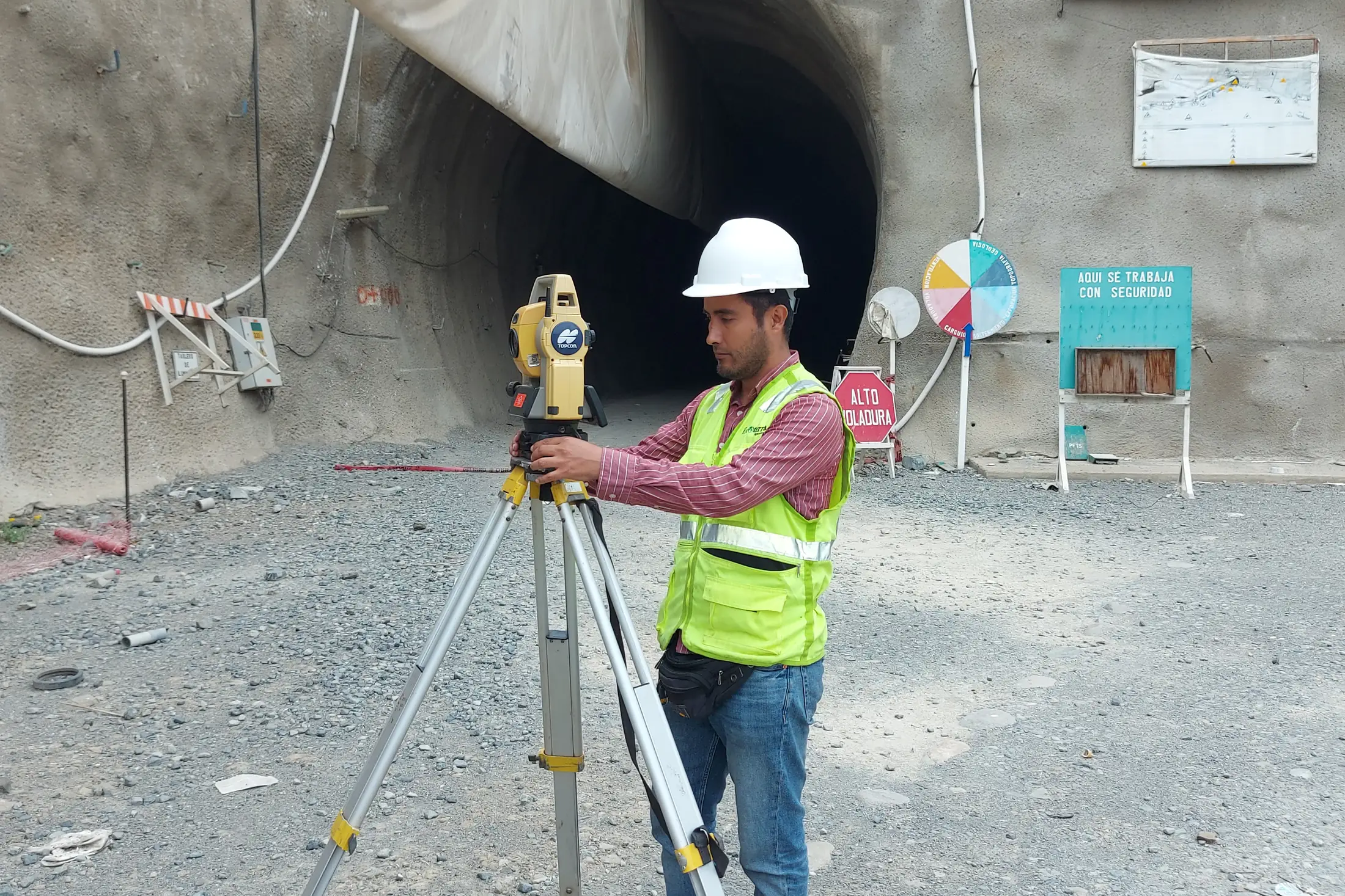 Topógrafo operando una estación total frente a la bocamina de un túnel