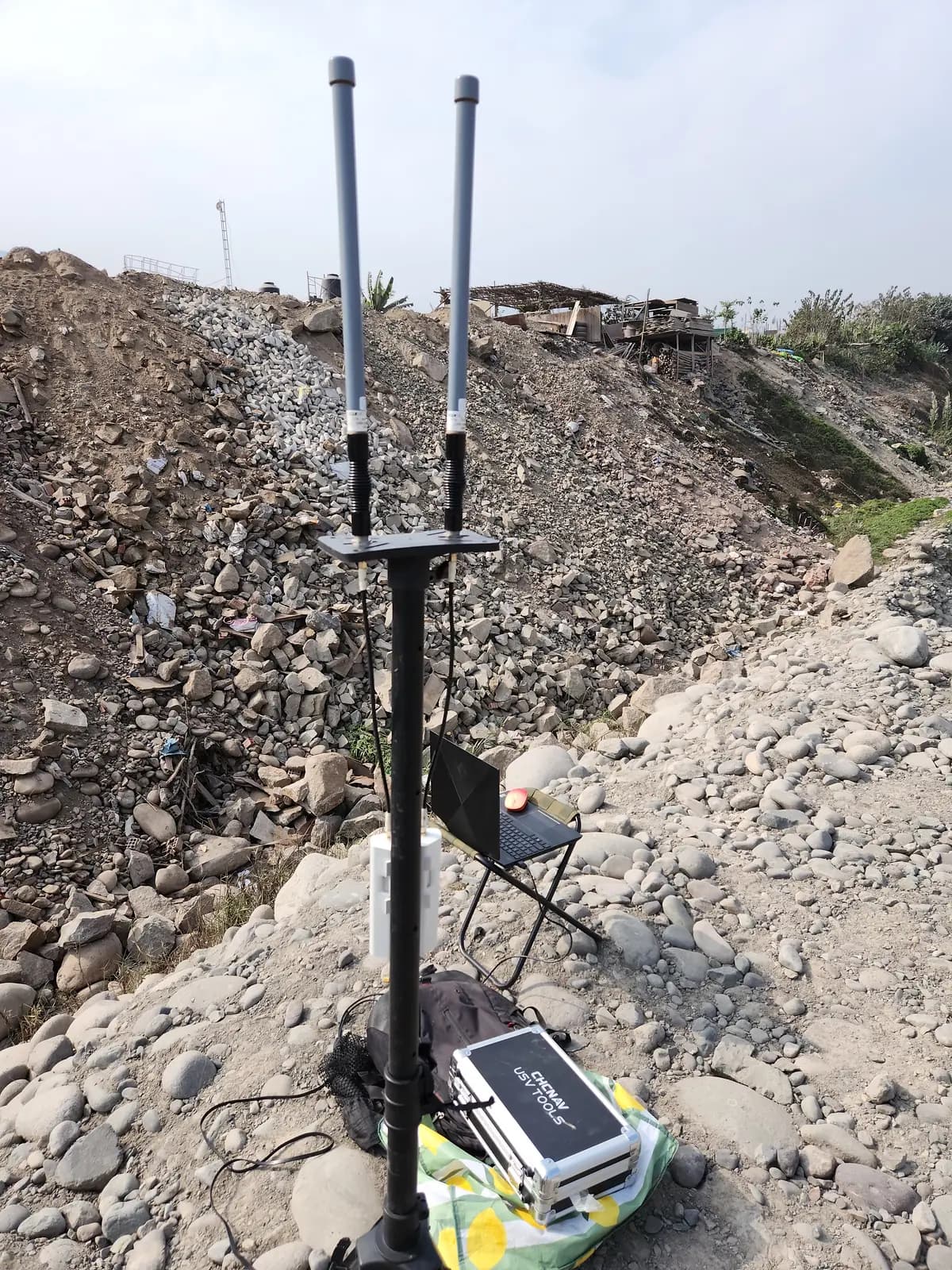 Estación de control en la orilla con antenas de radio y laptop para el levantamiento batimétrico
