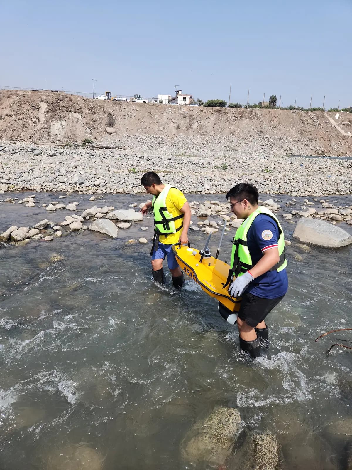 Dos técnicos trasladan la embarcación de batimetría al cauce del río
