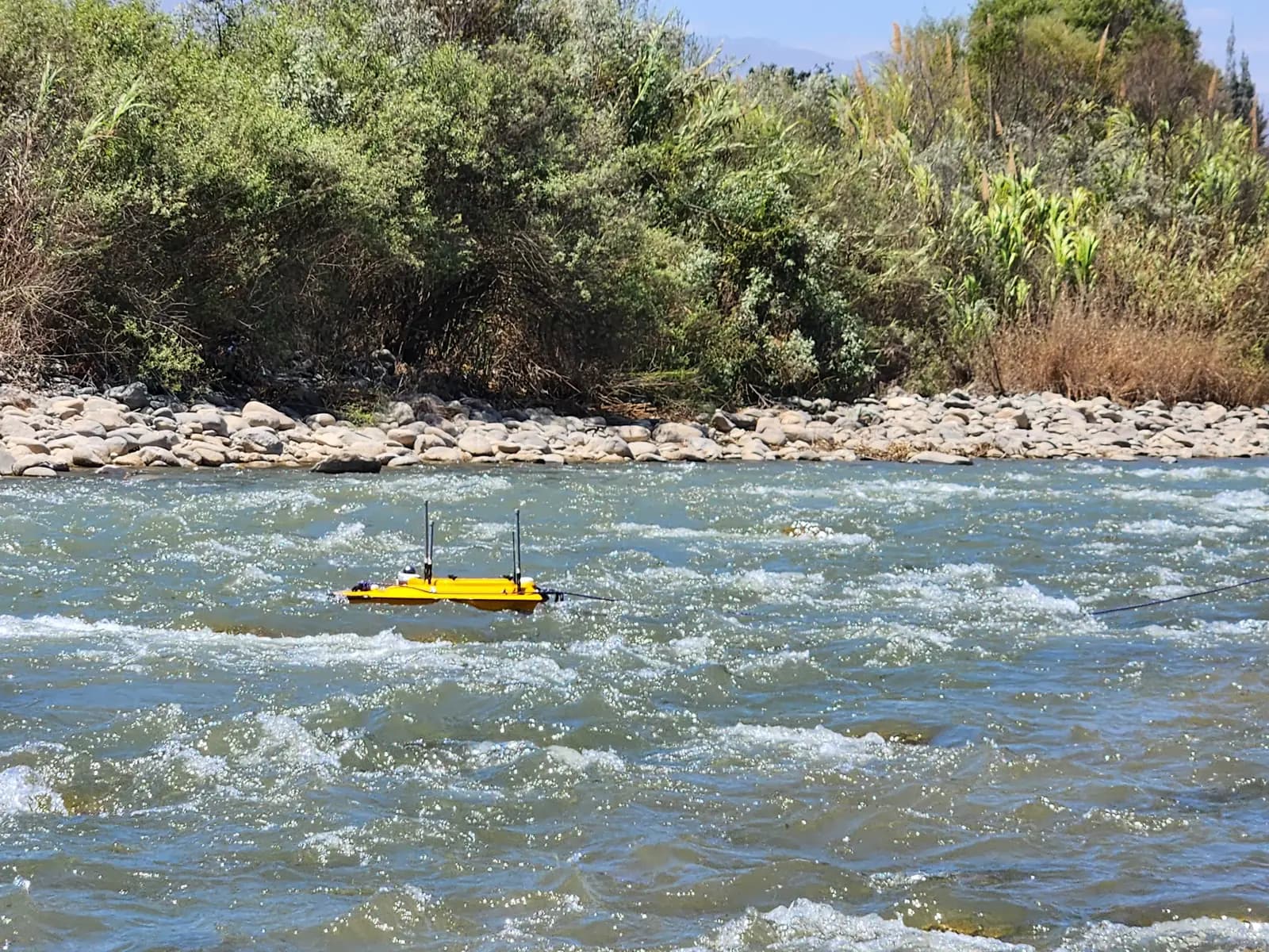 Embarcación no tripulada de batimetría navegando en un tramo de río con corriente