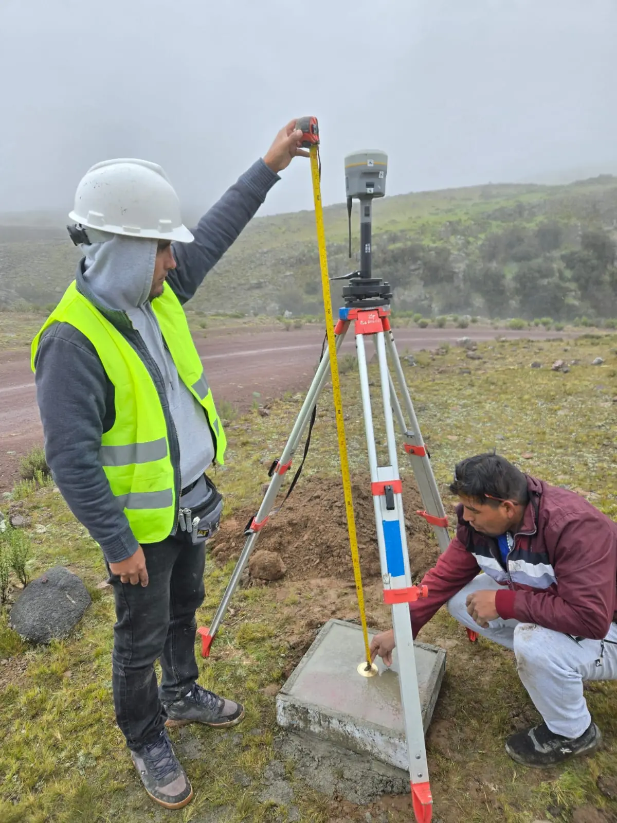 Técnicos midiendo la altura de la antena GNSS sobre el hito geodésico