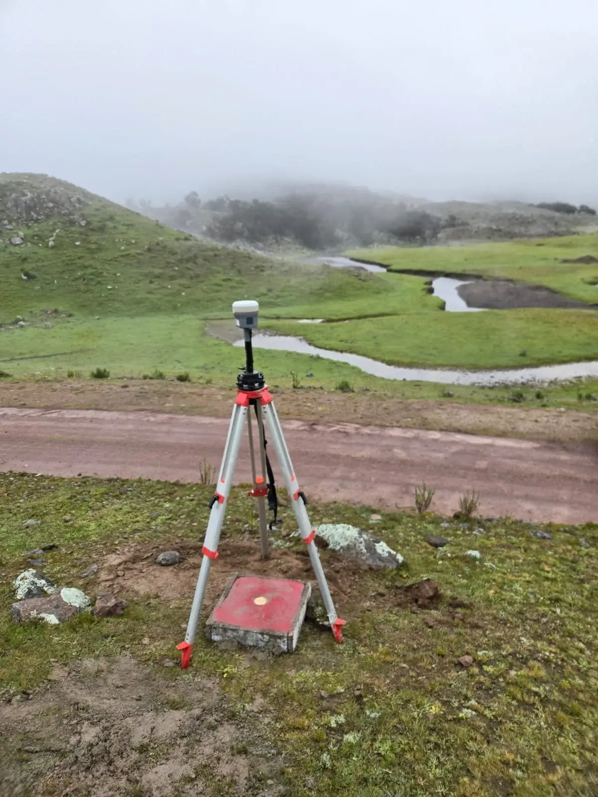 Receptor GNSS sobre un hito en un valle altoandino con neblina