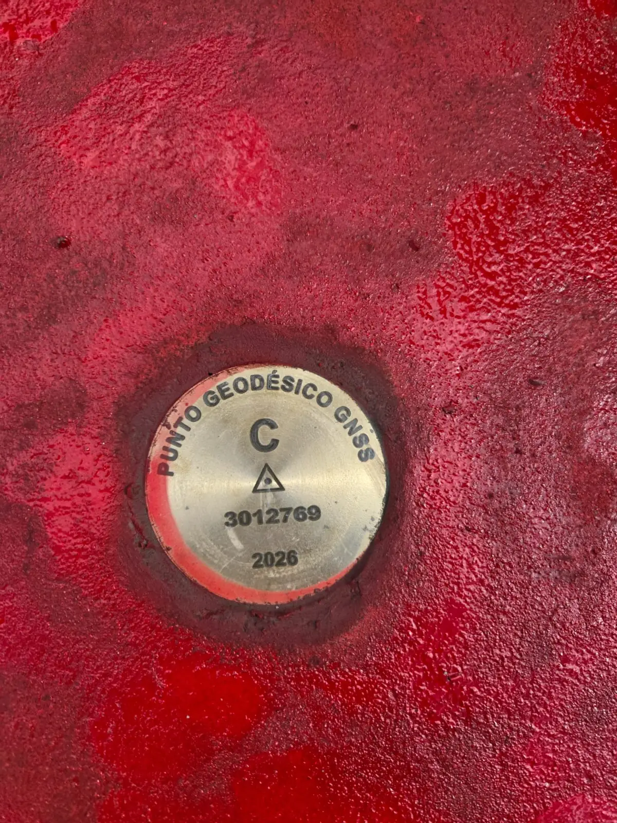 Placa de bronce de un punto geodésico GNSS de orden C empotrada en el hito