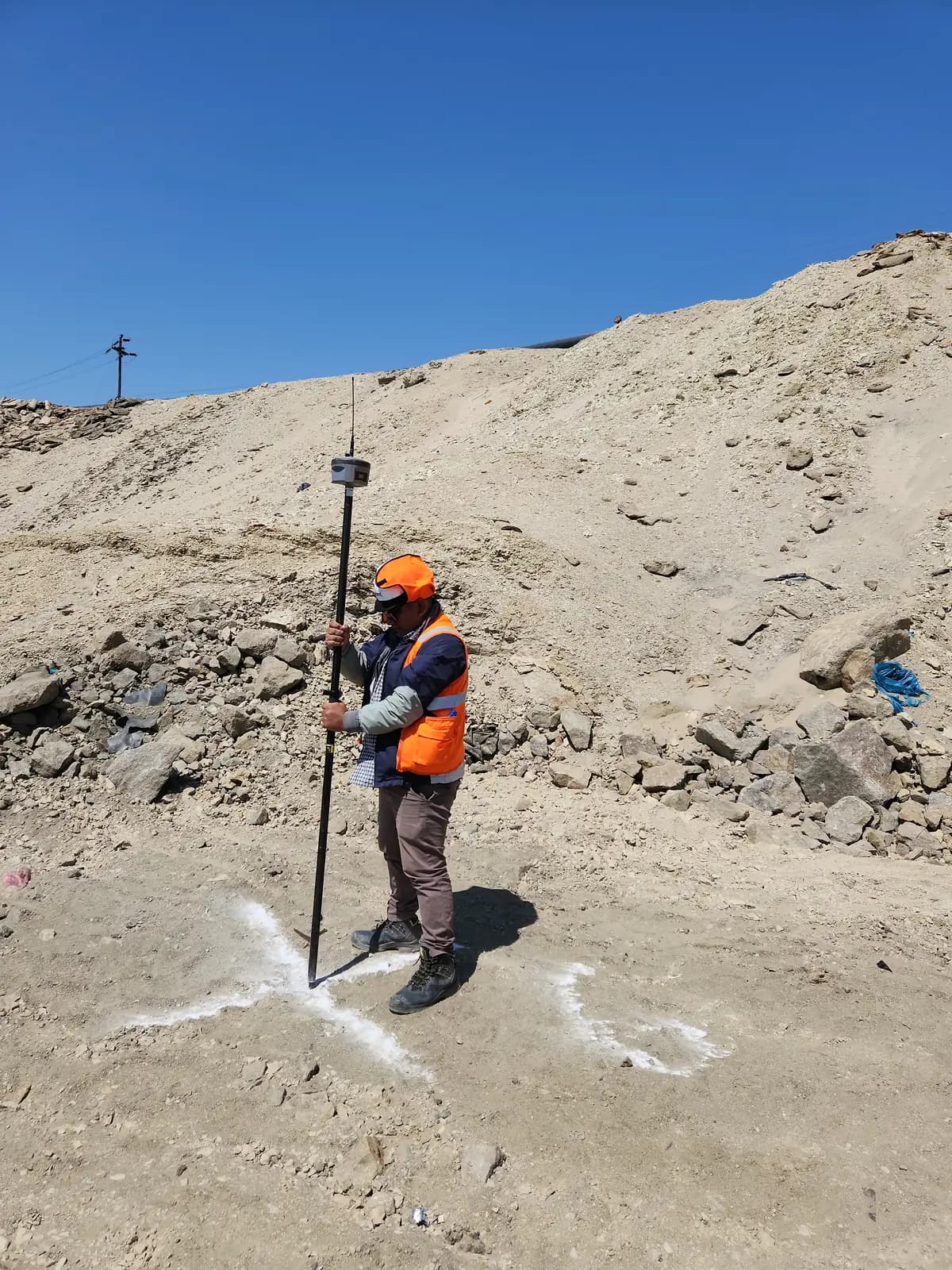 Técnico replanteando un punto con receptor GNSS RTK en un terreno de obra