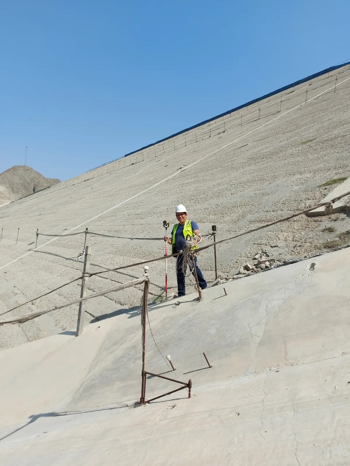 Topógrafo realizando control topográfico sobre el talud de una presa
