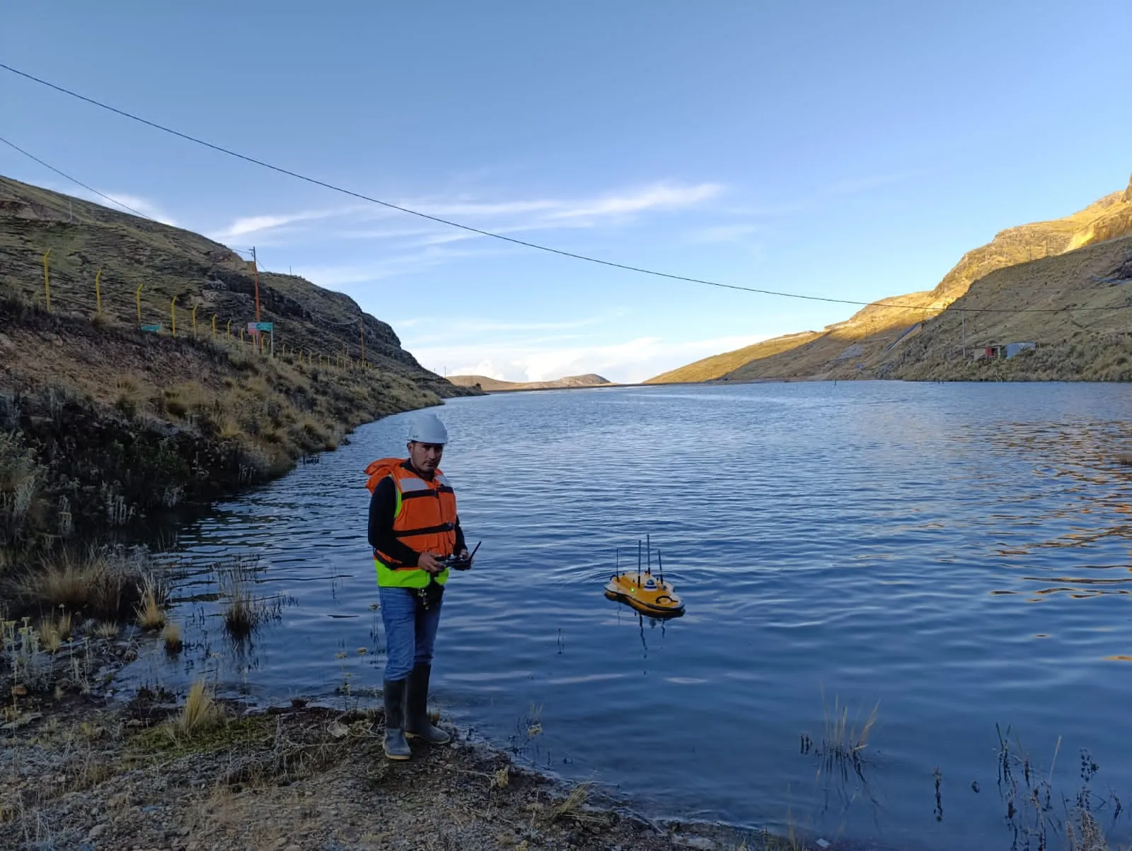 Técnico operando una embarcación no tripulada con ecosonda en un embalse andino